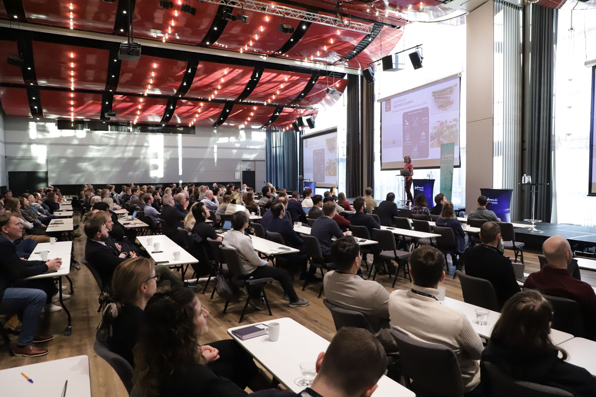 A large group of people in a room, attending a conference.